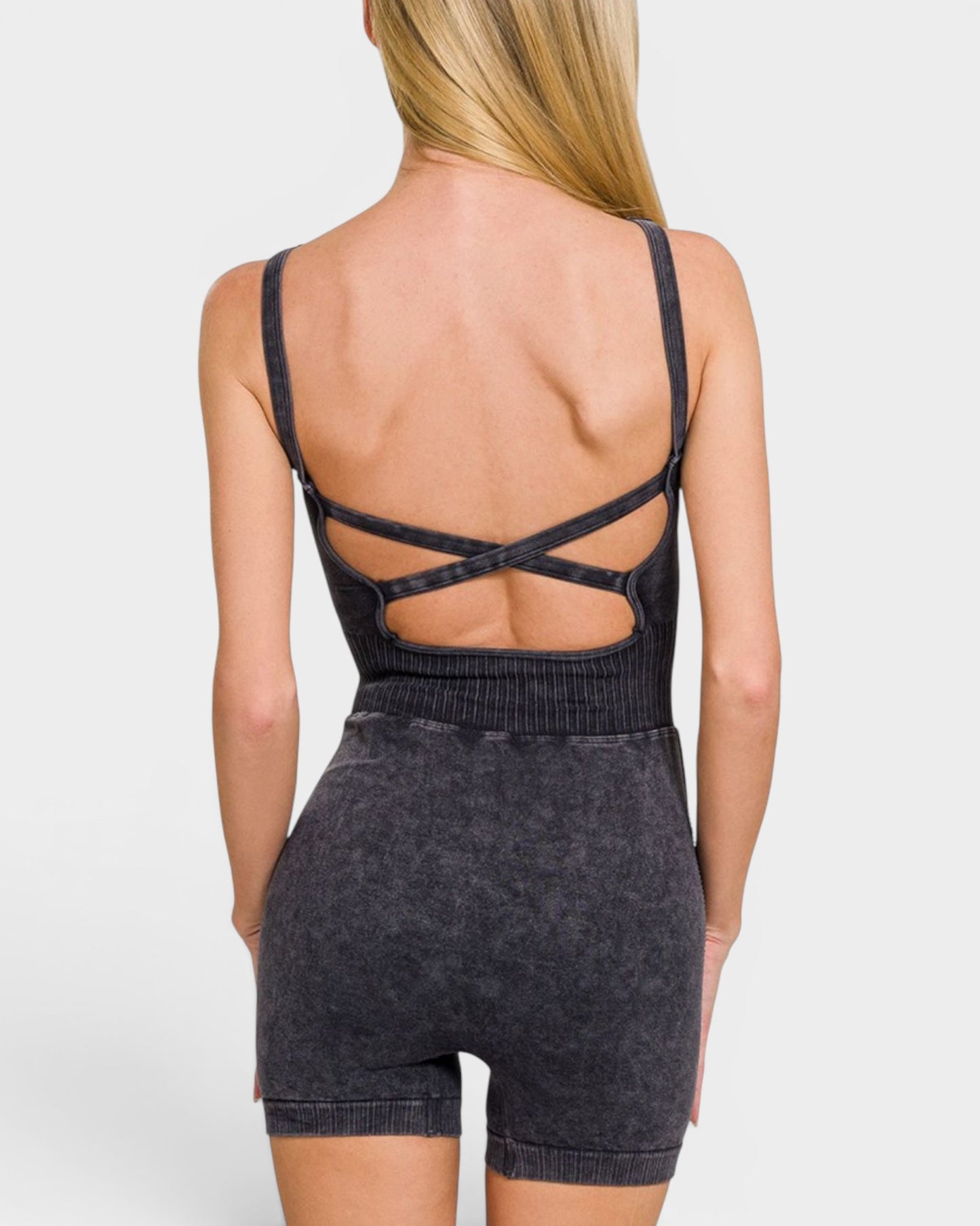 Person wearing a black open-back top and shorts on a light gray background