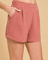 Pink shorts worn by a person on a beige background