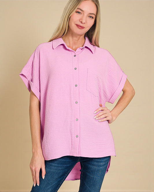 Woman wearing a pink button-up shirt with short sleeves on a beige background