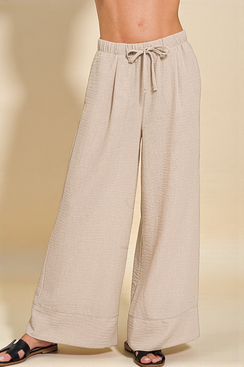Beige wide-leg pants with a drawstring waist on a beige background