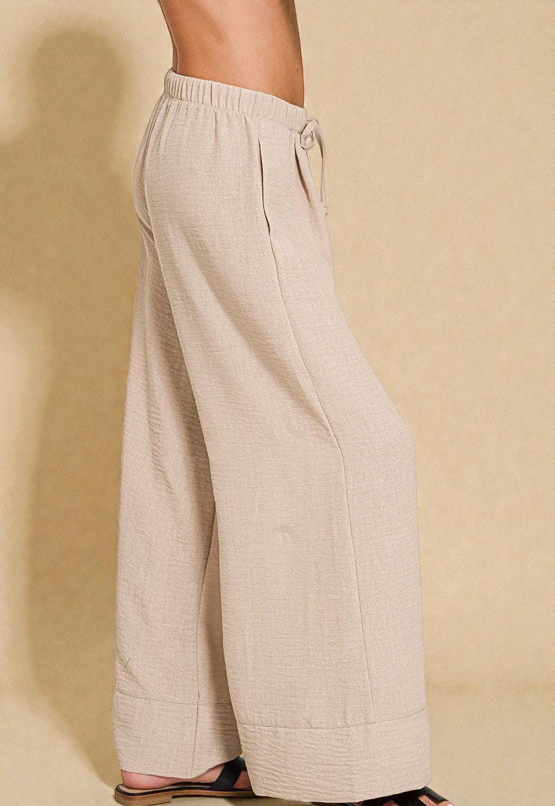 Beige wide-leg pants worn by a person on a beige background