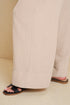 Person wearing beige pants and black sandals on a beige background