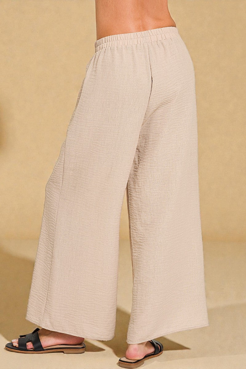Beige wide-leg pants worn by a person on a beige background