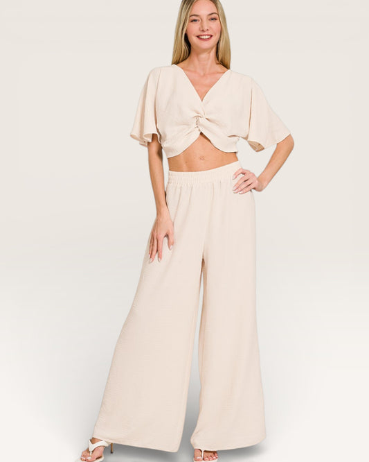 Woman wearing a beige outfit with a top and wide-leg pants on a white background