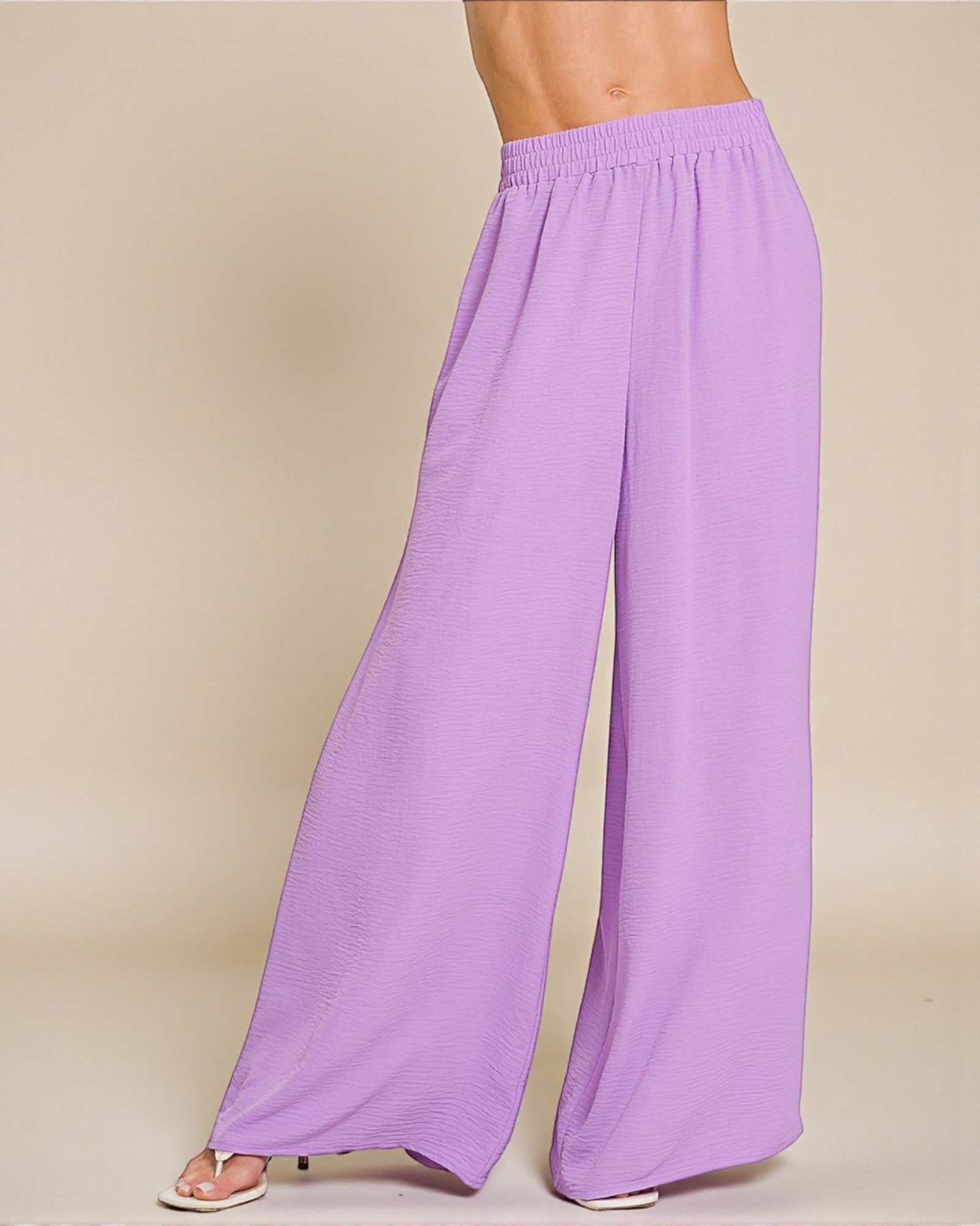 Purple wide-leg pants worn by a person on a beige background