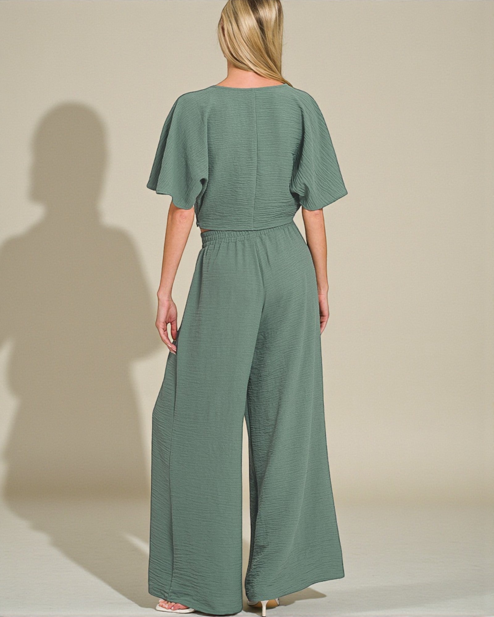 Woman wearing a green jumpsuit against a plain background
