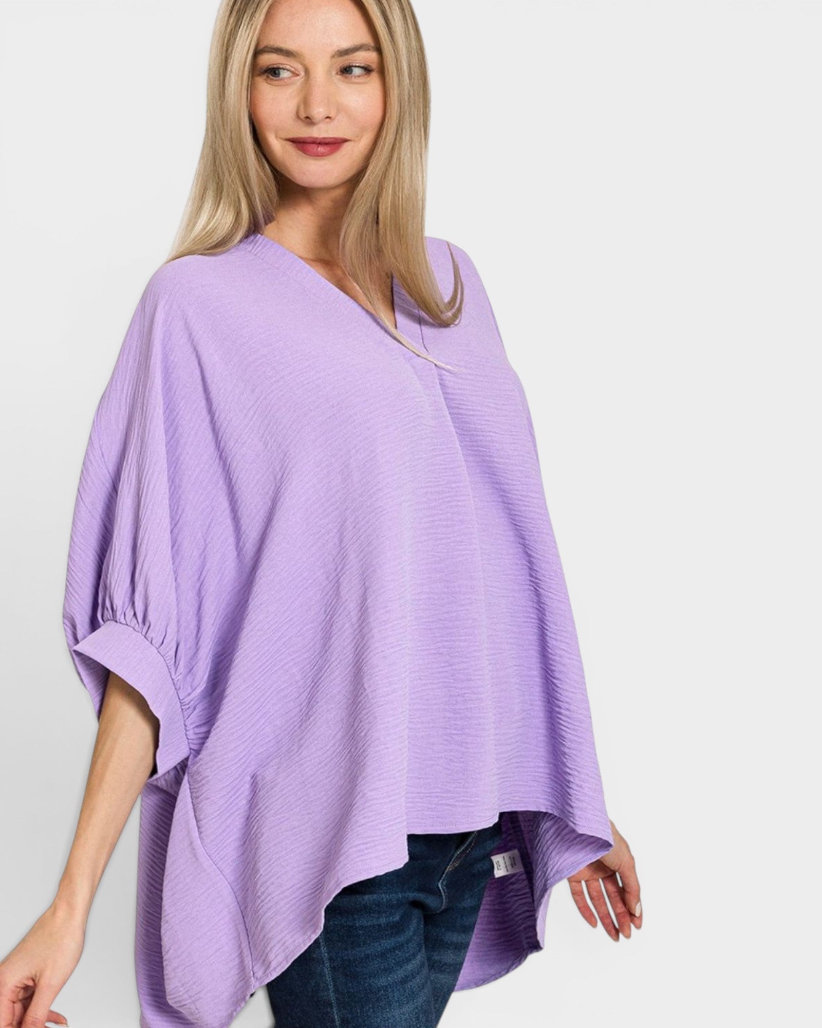 Woman wearing a light purple poncho over a white background