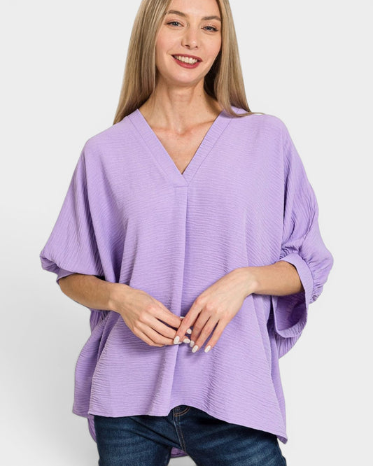 Woman wearing a purple poncho against a white background