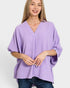 Woman wearing a purple poncho against a white background