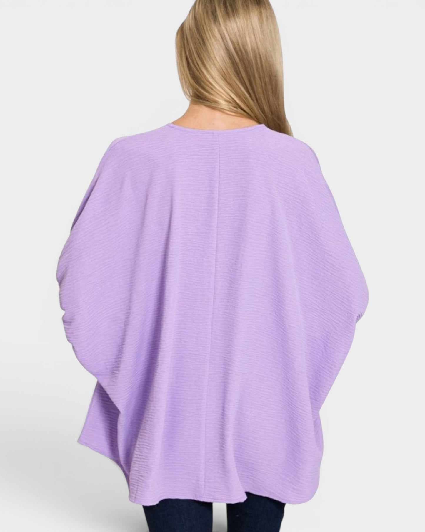 Person wearing a light purple poncho against a white background
