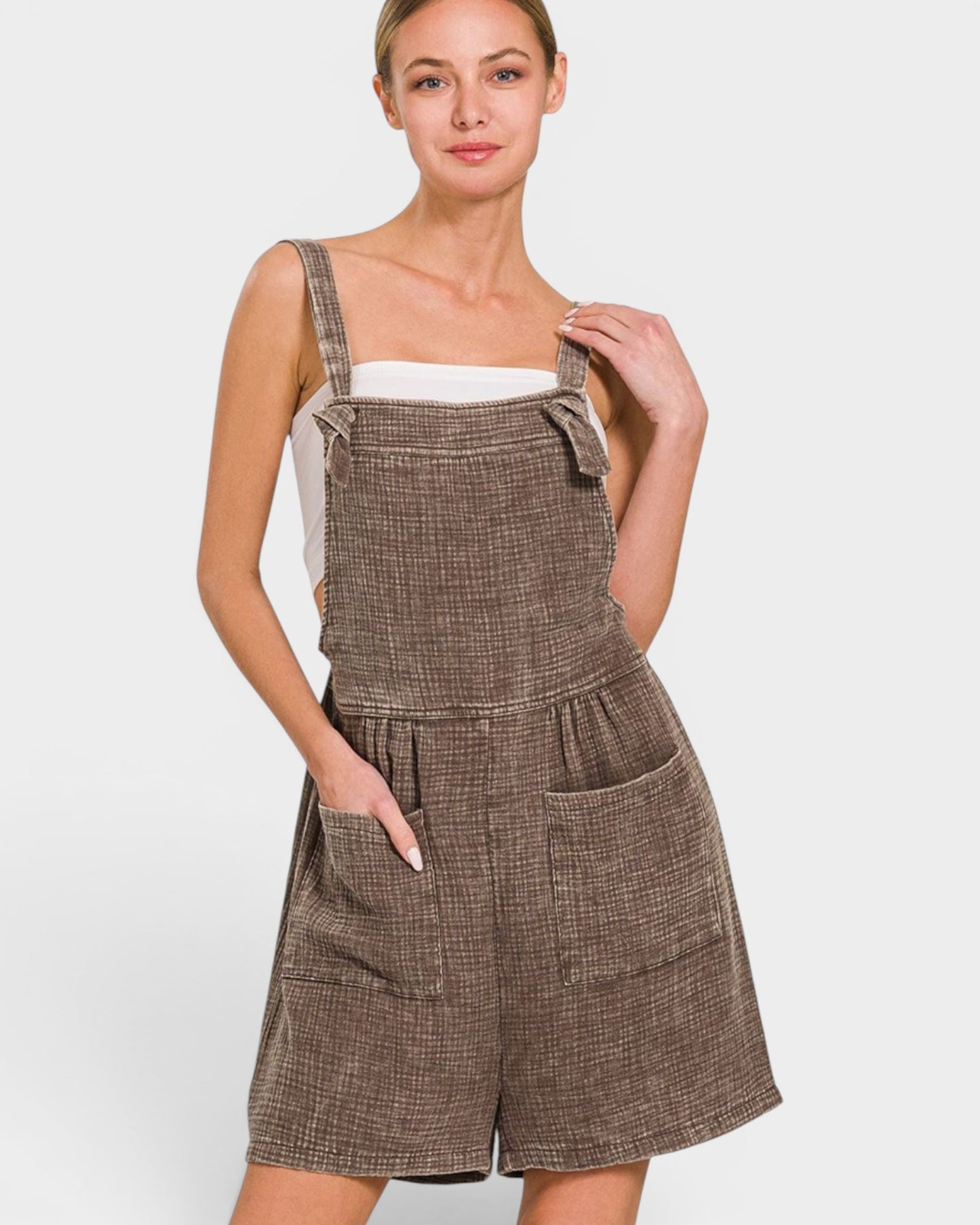 Woman wearing a brown checkered pinafore dress on a white background