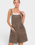 Woman wearing a brown checkered pinafore dress on a white background