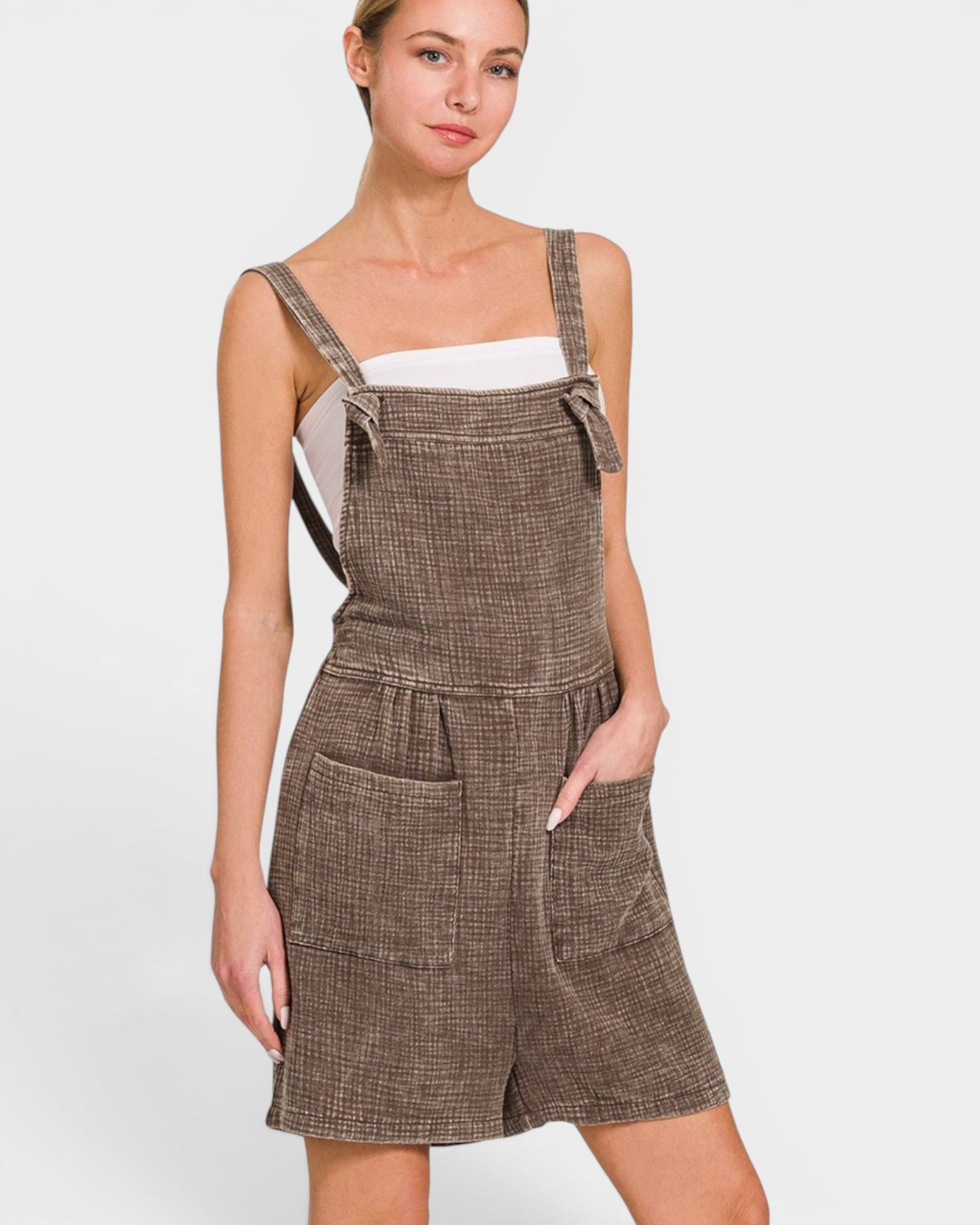 Woman wearing a brown checkered pinafore dress on a white background