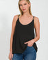 Woman wearing a black tank top and blue jeans on a white background
