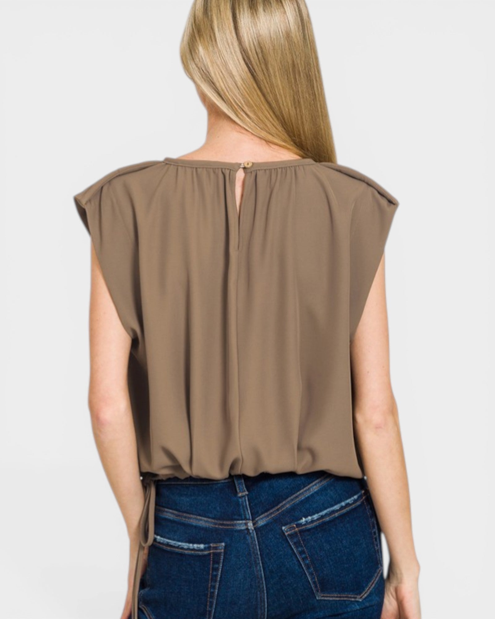 Brown sleeveless top worn by a person on a plain background