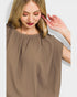 Woman wearing a brown blouse against a light background