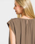 Woman wearing a brown sleeveless top against a white background