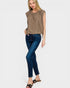 Woman wearing a brown sleeveless top and blue jeans on a white background