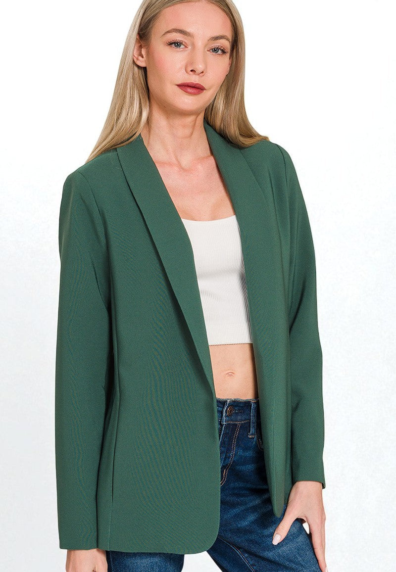Woman wearing a green blazer over a white top and blue jeans on a white background