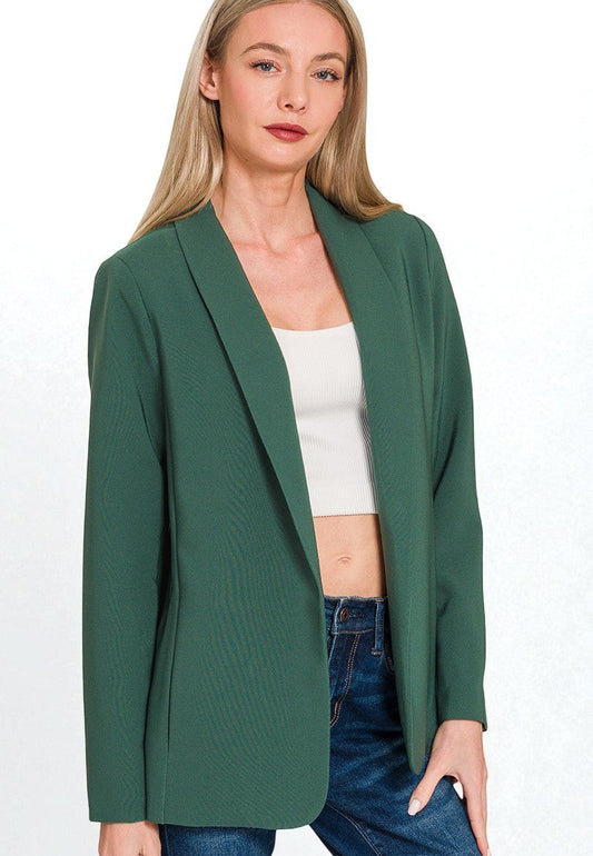 Woman wearing a green blazer over a white top and blue jeans on a white background