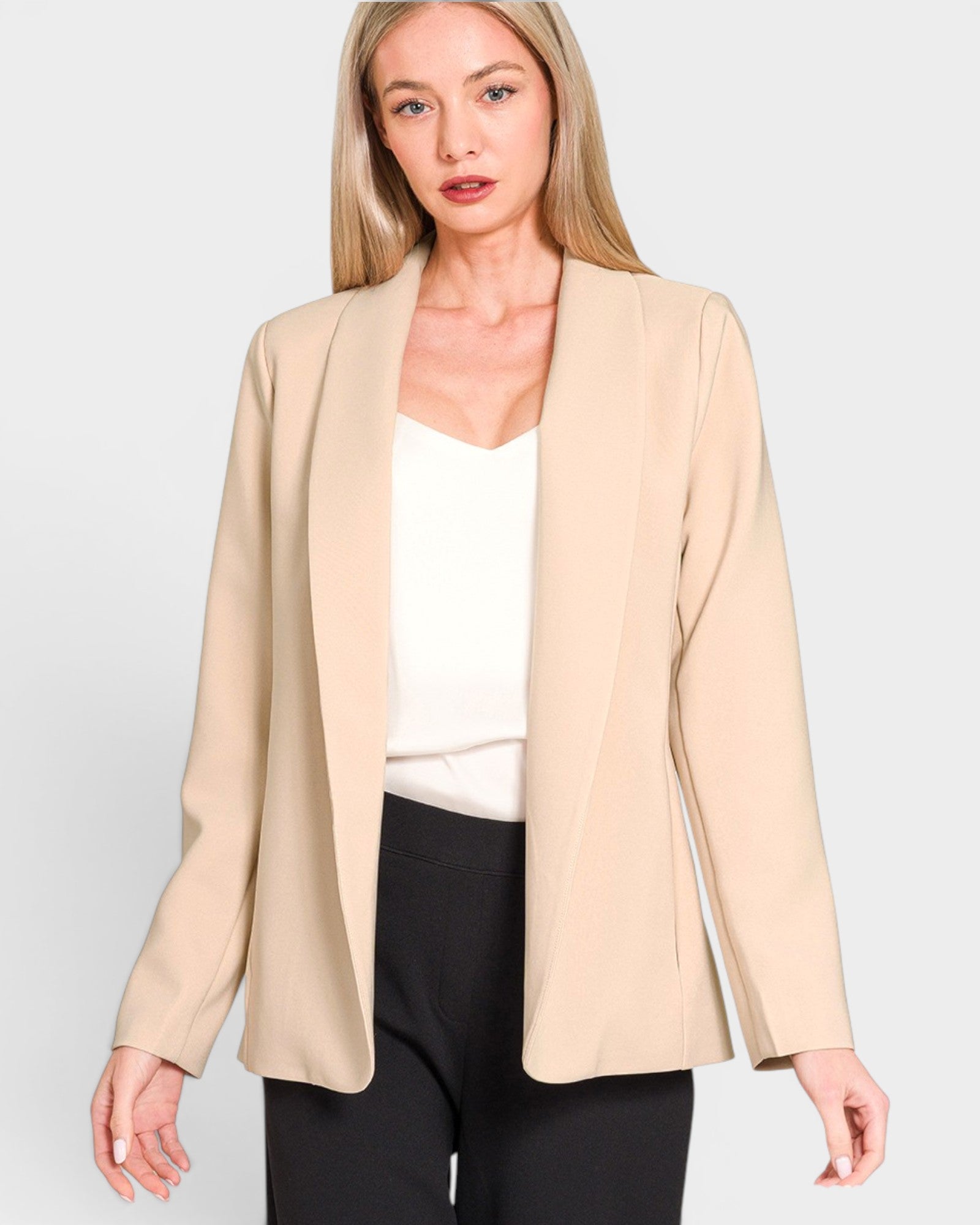 Woman wearing a beige blazer over a white top and black pants on a light gray background
