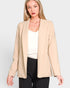 Woman wearing a beige blazer over a white top and black pants on a light gray background