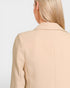 Beige blazer worn by a person on a light gray background
