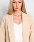 Woman wearing a beige blazer over a white top against a plain background