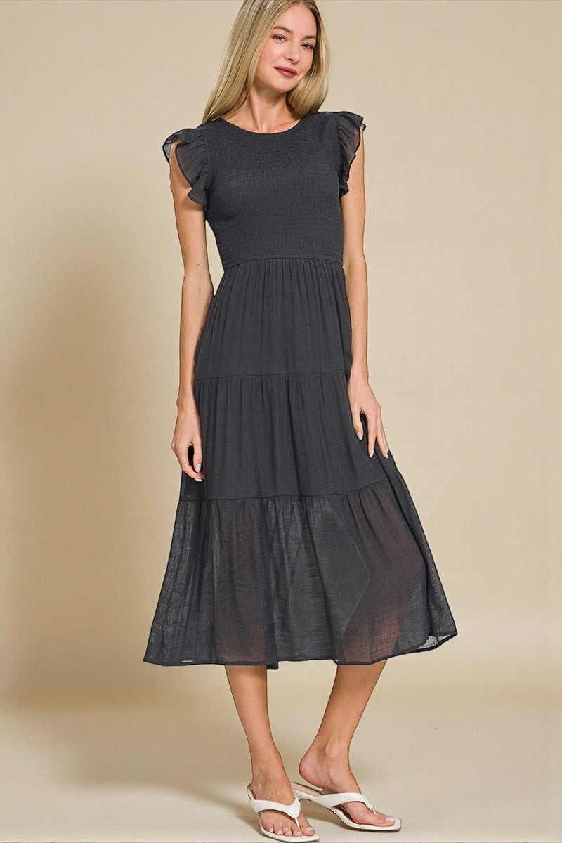 Woman wearing a black dress with sheer panels on a beige background