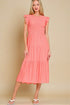 Woman wearing a coral dress with ruffled sleeves against a beige background