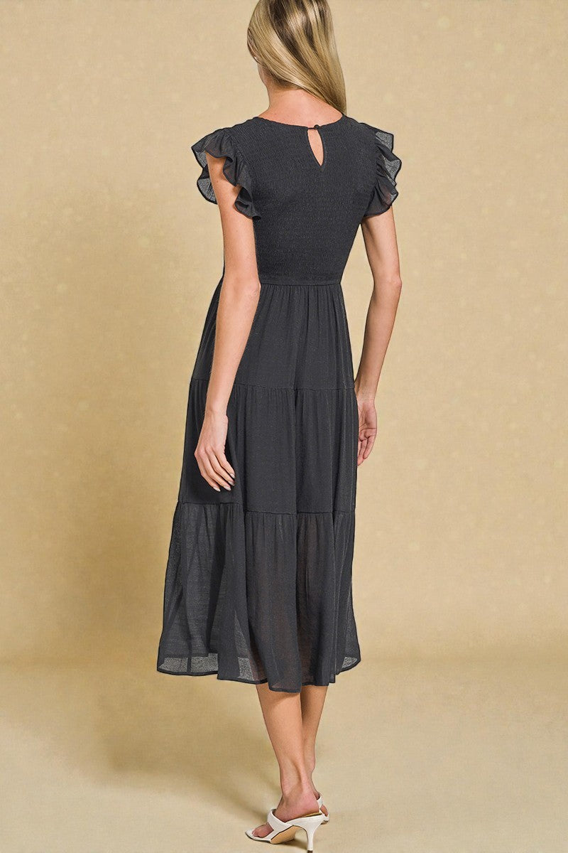 Woman wearing a black dress with ruffled sleeves on a beige background