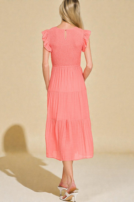 Woman wearing a coral dress against a beige background