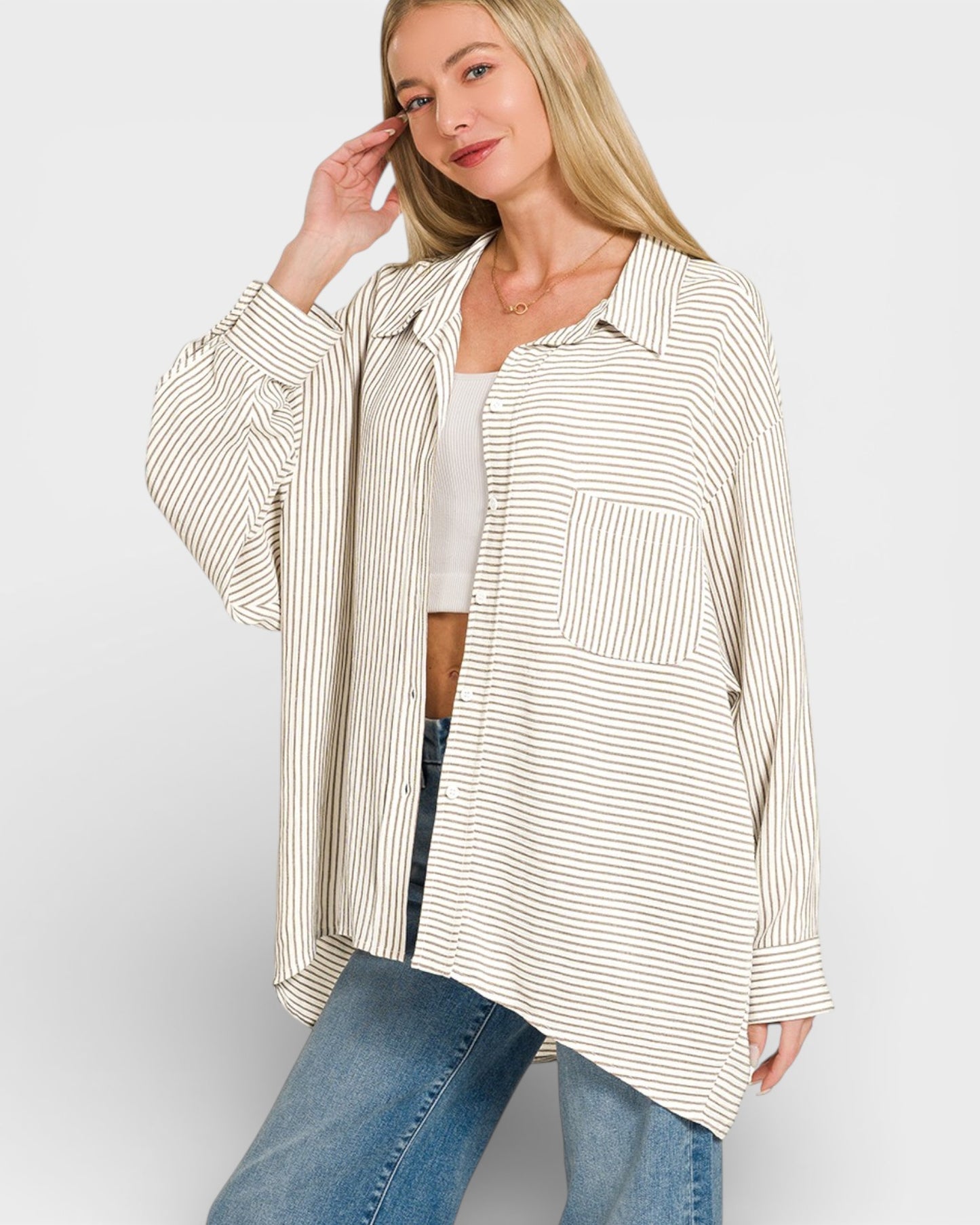 Woman wearing a striped shirt and jeans on a plain background