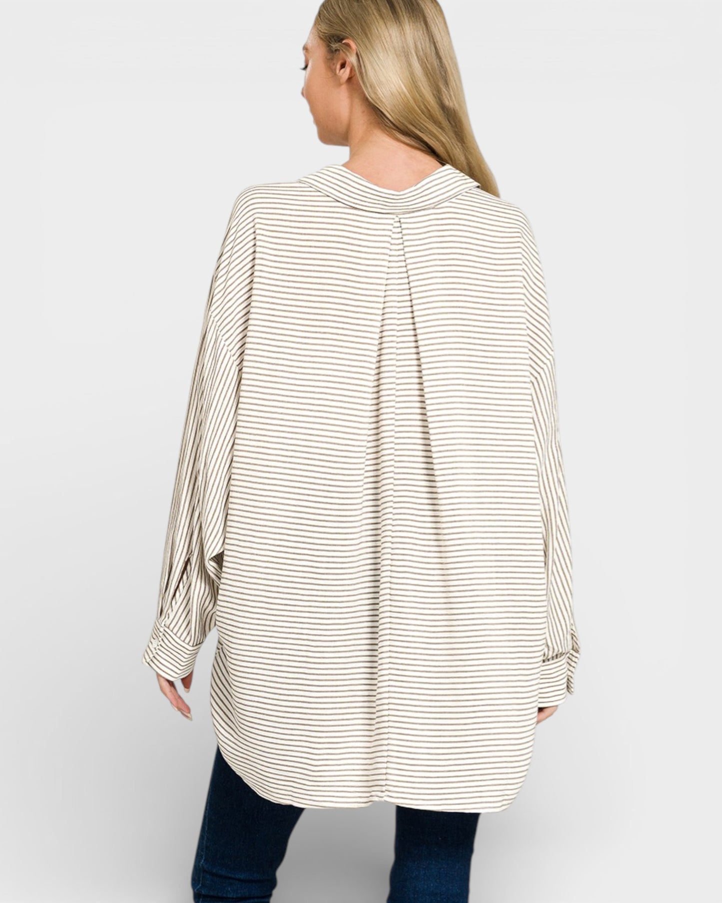 Woman wearing a long, striped shirt on a plain background