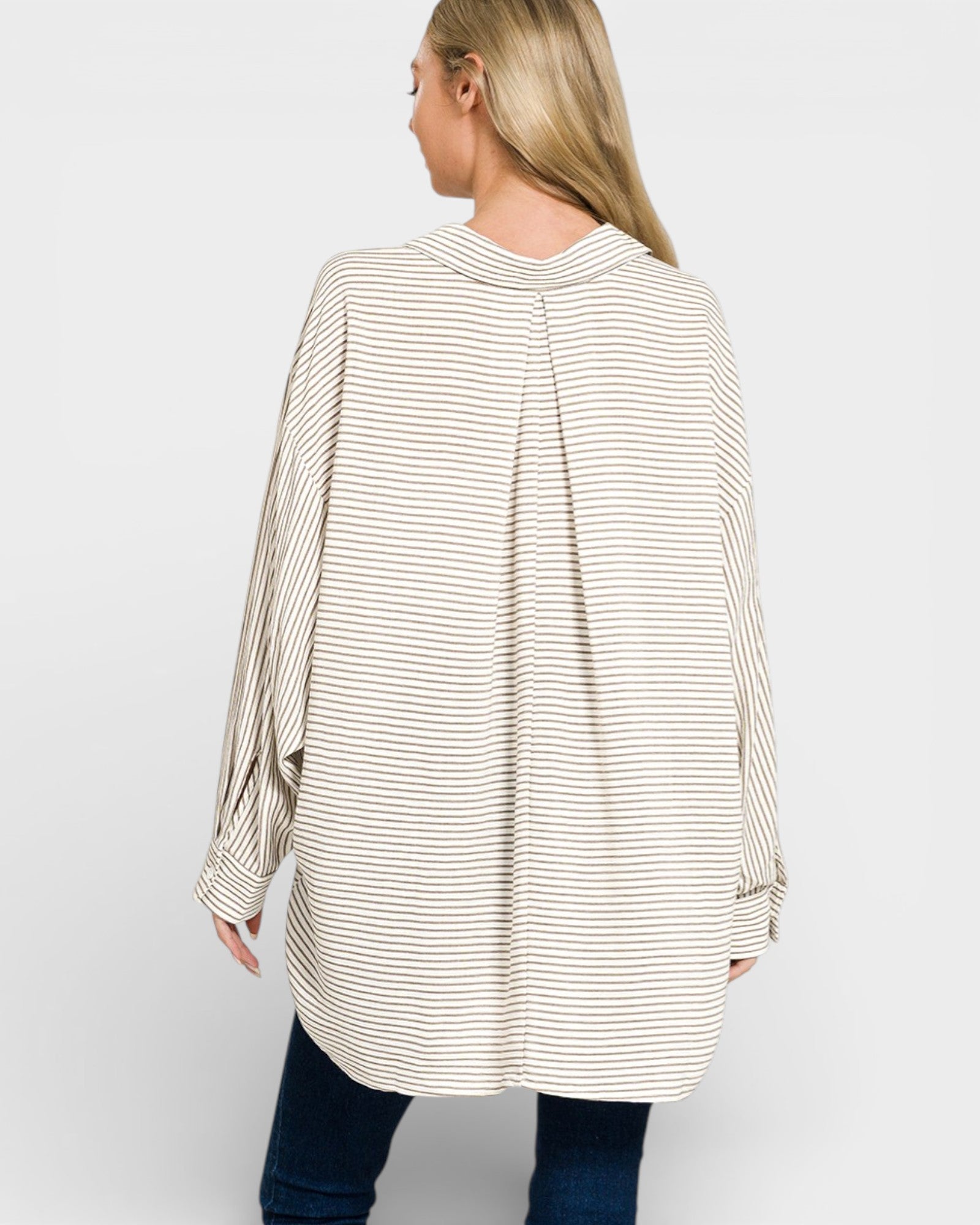 Woman wearing a long, striped shirt on a plain background