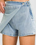 Close-up of a person wearing light blue denim shorts on a plain background