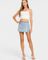 Woman wearing a white top and denim skirt on a plain background