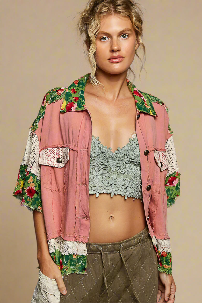 Woman wearing a pink jacket with floral embroidery on a gray background