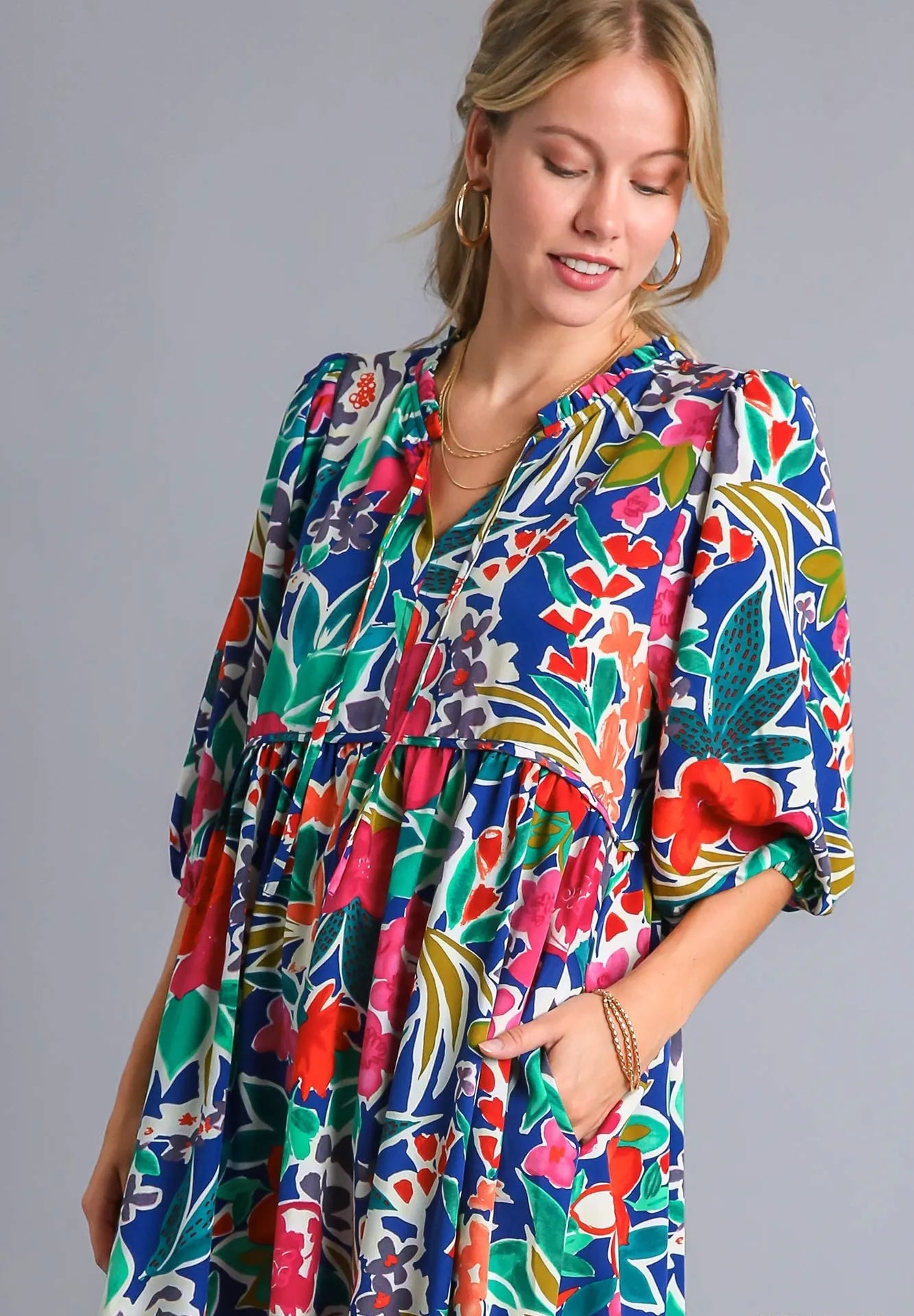 Woman wearing a colorful patterned dress on a gray background