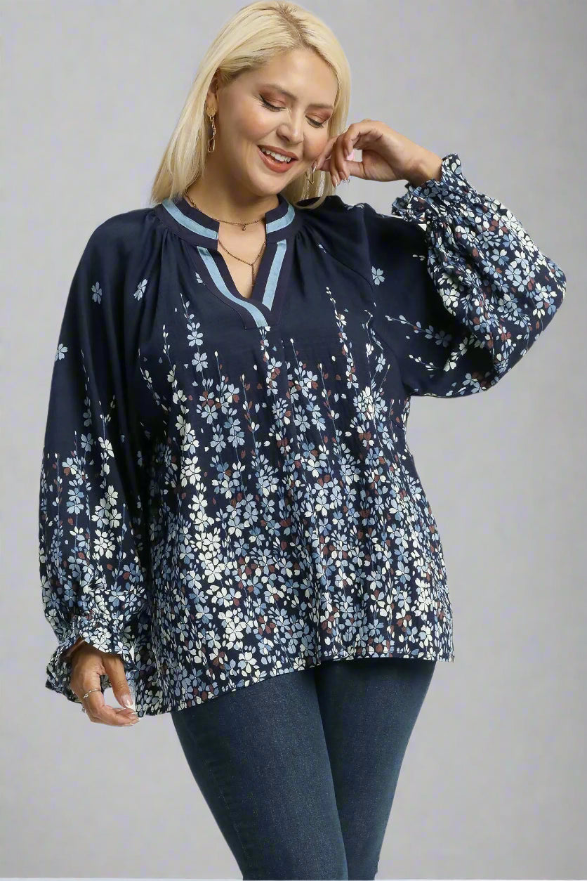 Woman wearing a navy floral blouse with blue jeans on a white background