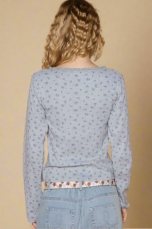 Person wearing a light blue floral long-sleeve top and jeans against a beige background