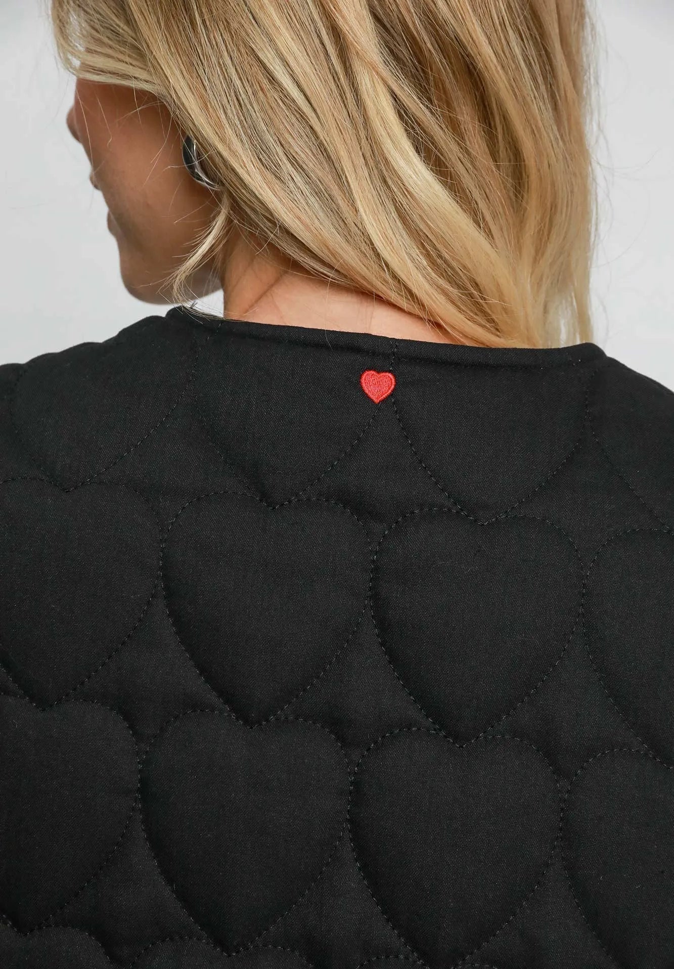 Black textured garment with a red heart detail on a plain background