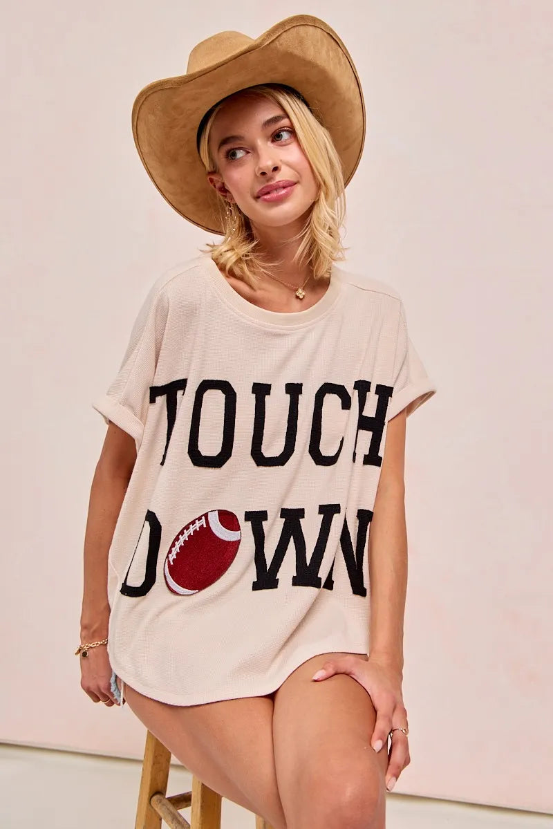 Woman wearing a 'Touchdown' t-shirt with a football graphic on a plain background