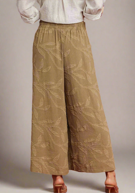 Brown patterned pants worn by a person on a red background