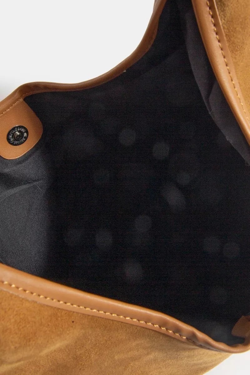Close-up of a brown leather bag with black interior