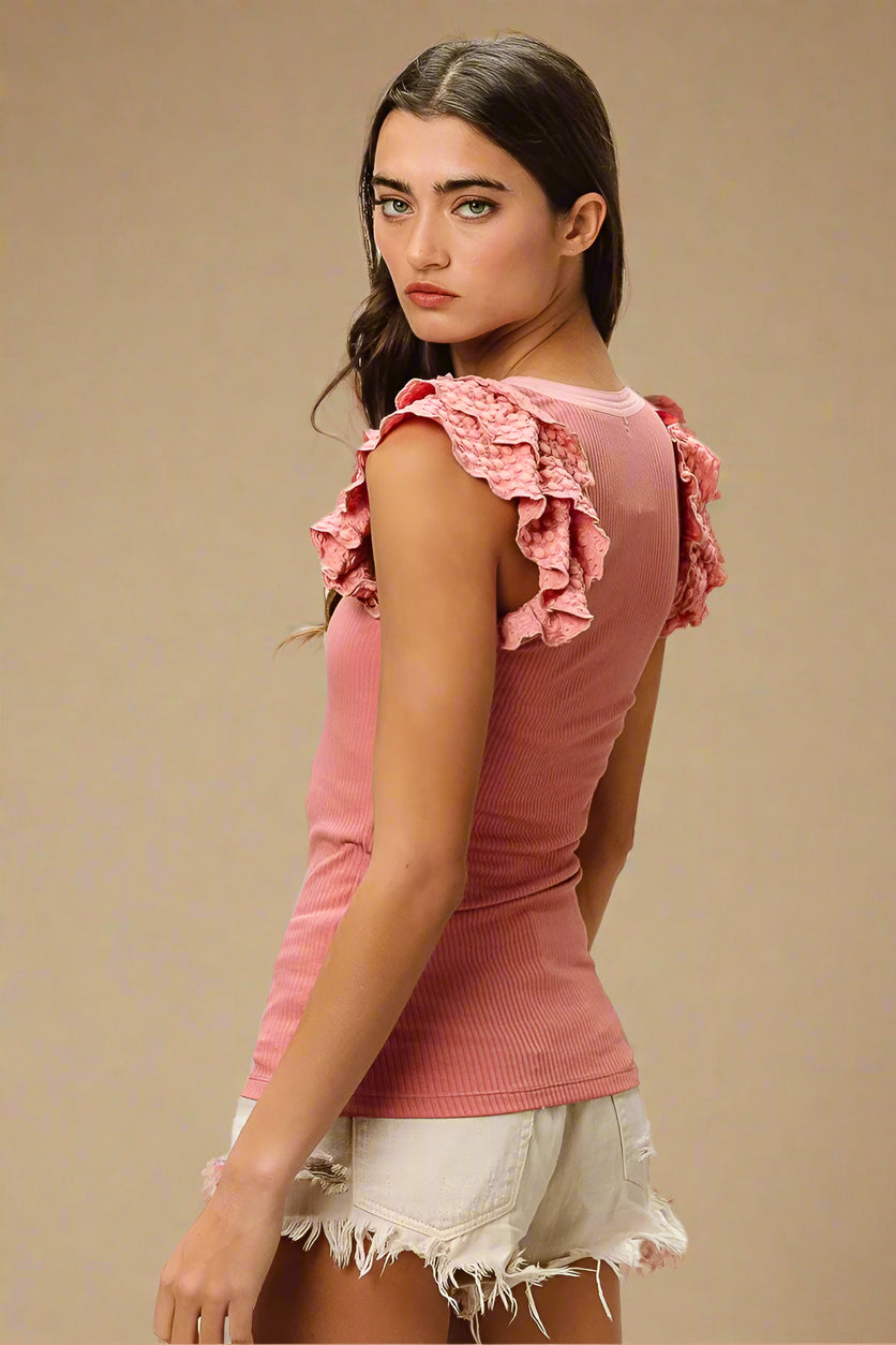 Woman wearing a pink top with ruffled sleeves on a beige background
