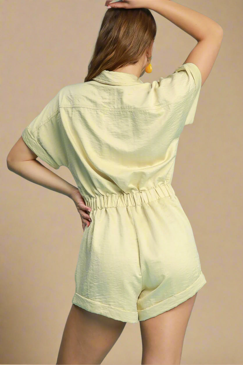 Woman wearing a light yellow romper against a solid background