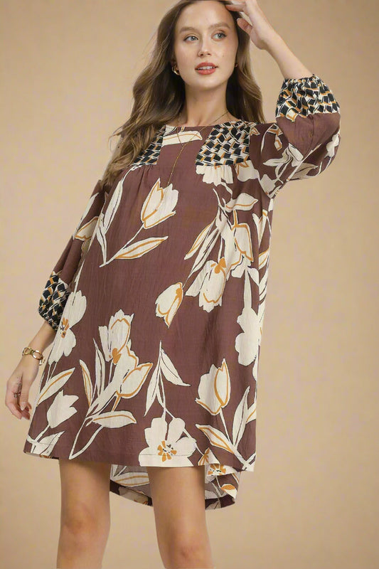 Woman wearing a floral dress with checkered sleeves on a beige background