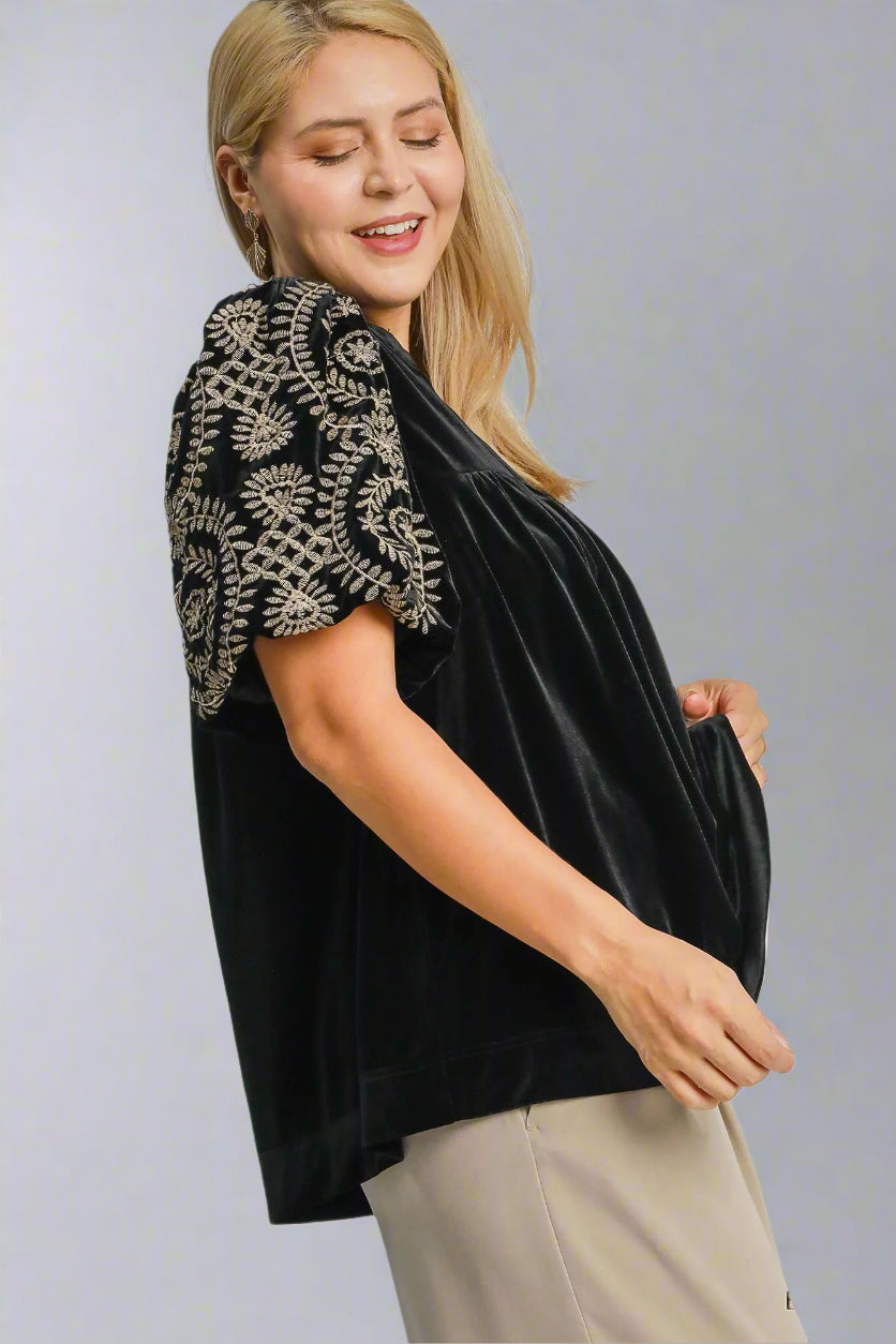 Woman wearing a black blouse with floral sleeves on a white background