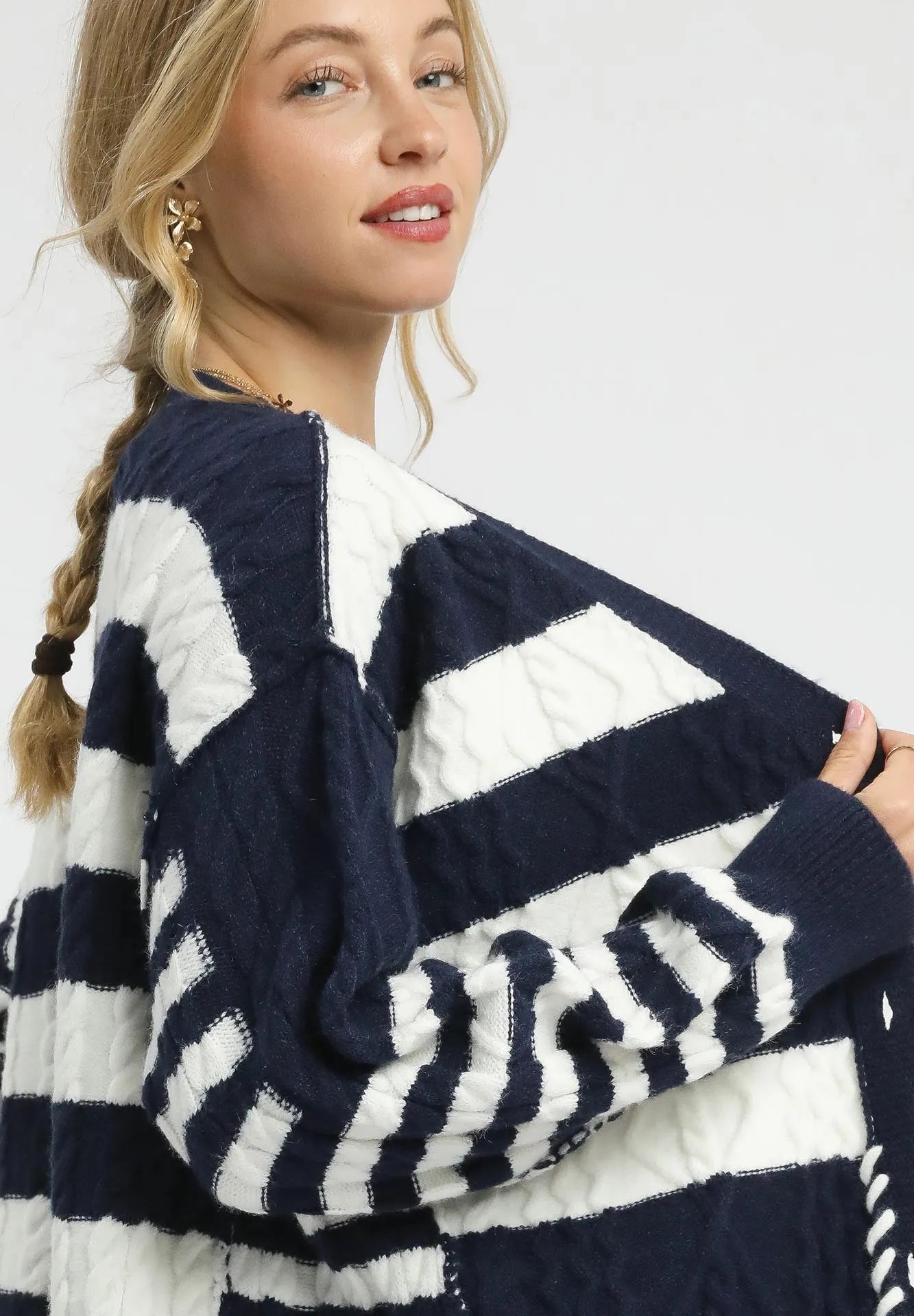 Woman wearing a navy and white striped sweater with a braided hairstyle.